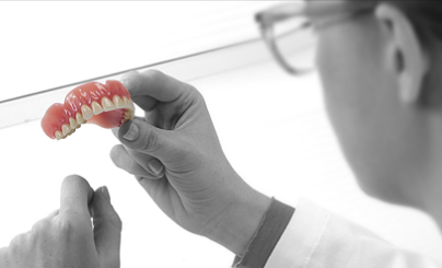 Lab technician looking at dental denture in black and white